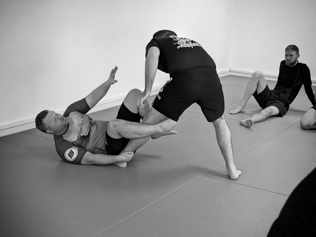 Two adults drilling a Brazilian Jiu Jitsu guard pass on the mats at the Abingdon dojo