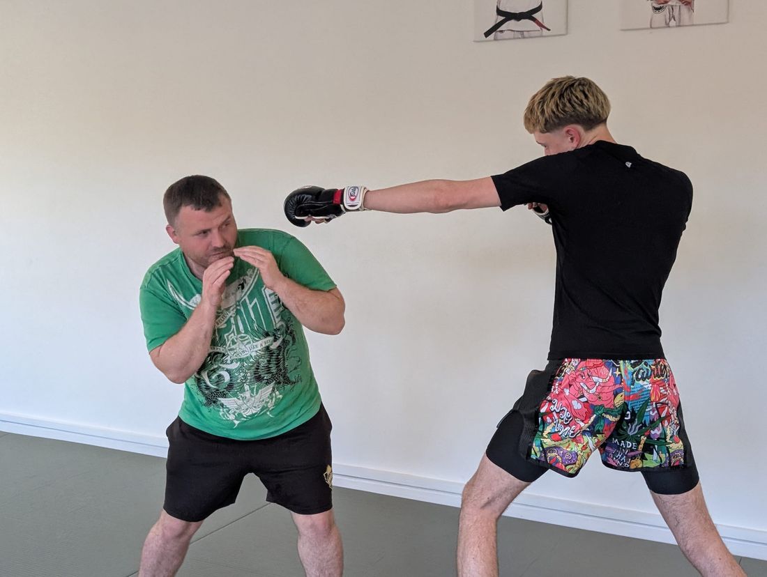 Adults practising Jeet Kune Do striking drills with focus mitts